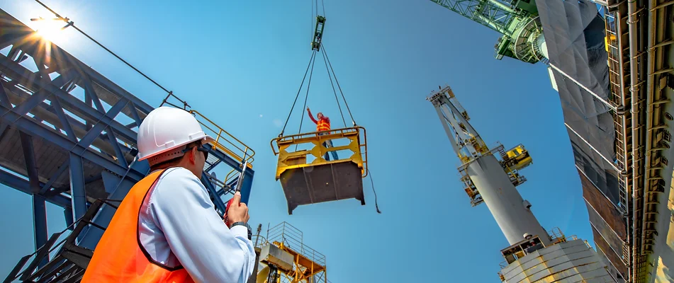 Man going up in a lift A man standing on top of a crane.