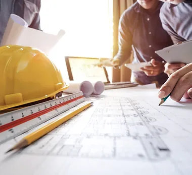 charts and scales placed together A group of people sitting around a table with construction plans.