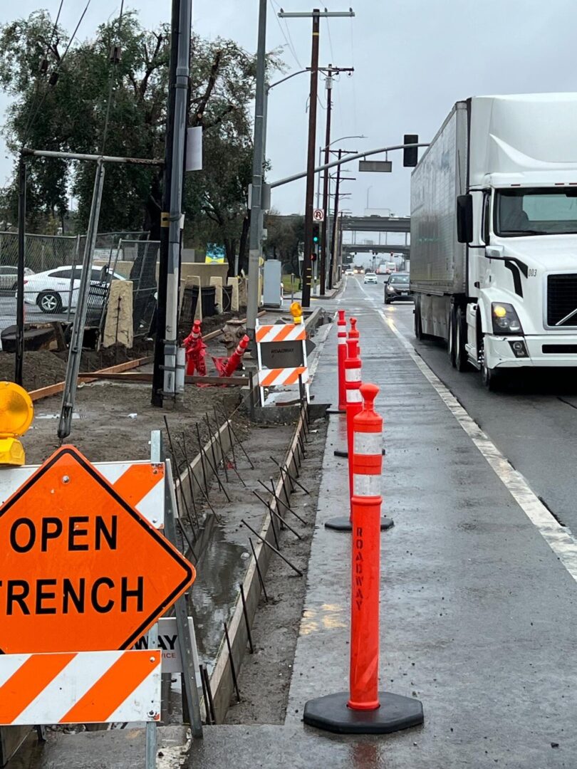 Road work with open trench and cones.