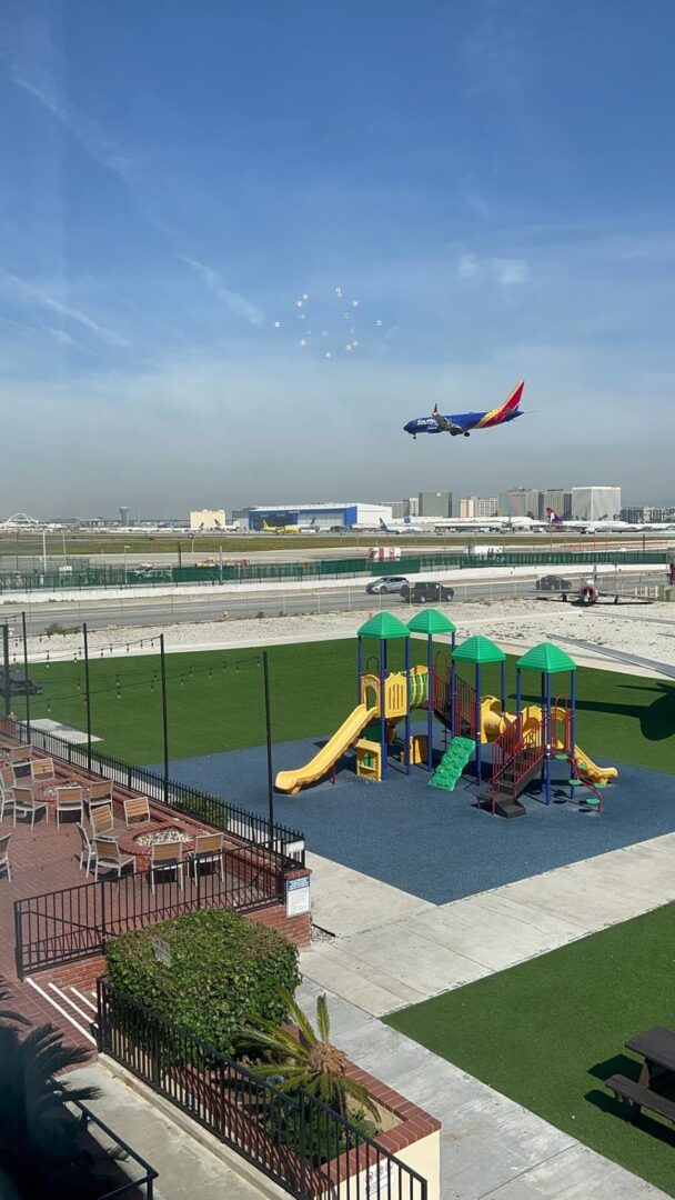 Airplane landing near a playground.