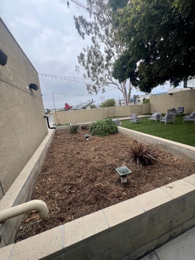 Mulched garden bed with drain pipes.