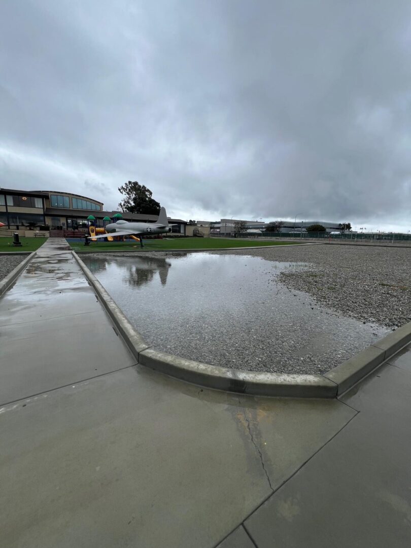 Wet concrete path with a puddle and a plane.