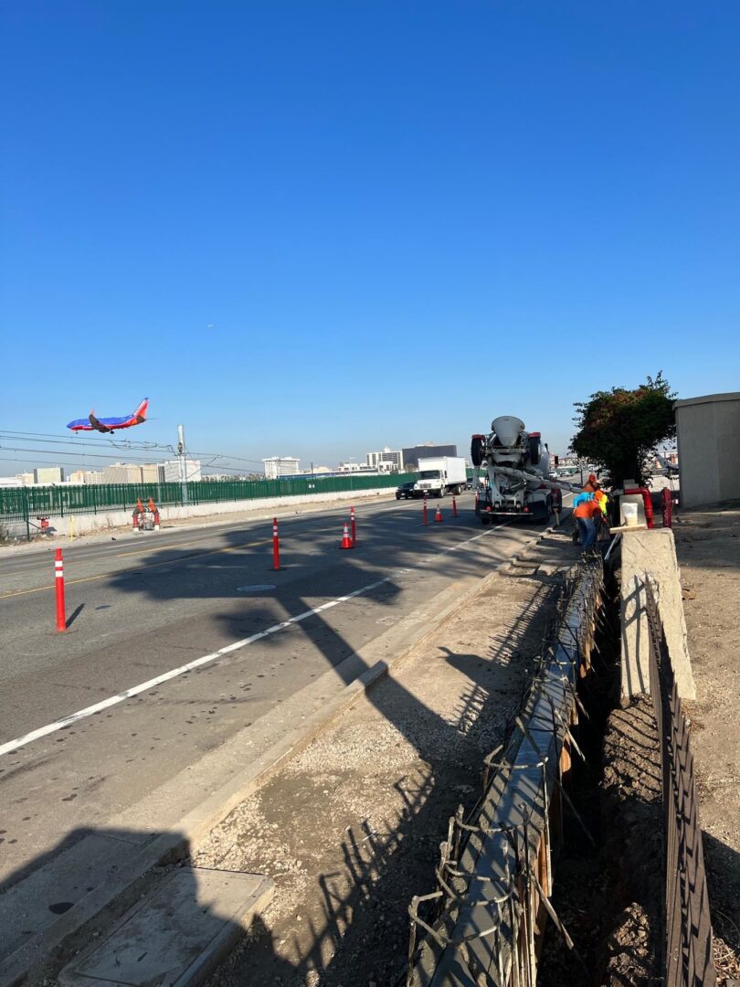 Road construction with airplane in background.