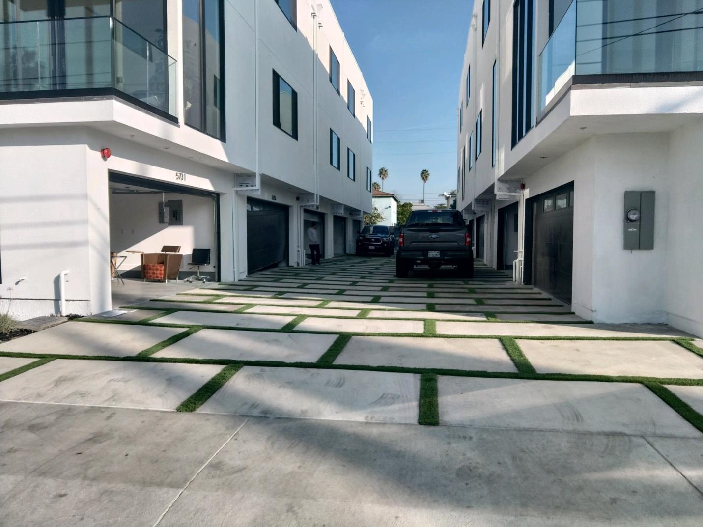 Modern white houses with grassy driveway.